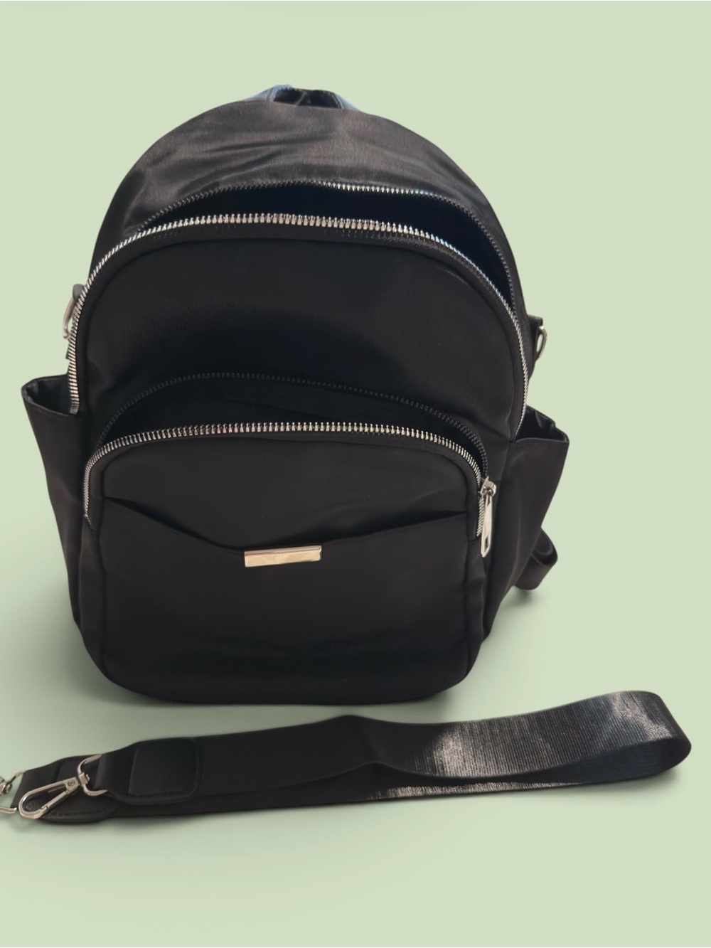 This black nylon backpack features a compact casual design with multiple Zippers